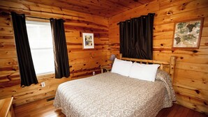 Een houten kamer met een bed, gordijnen en een lijst met een foto aan de muur.