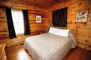 A wooden cabin room with a bed, curtains, and a framed picture on the wall. - 2 Bedroom 2 Bath Cabin with Hot Tub (Beaver, WV) (Beaver)