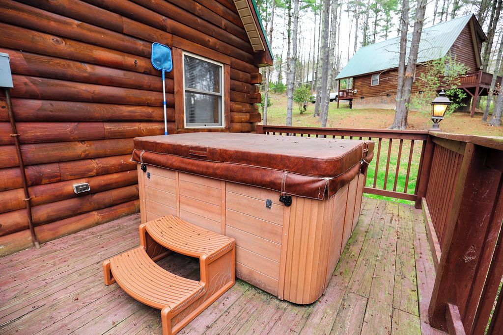 Una baita in legno con vasca idromassaggio e panchina di legno su un terrazzo.