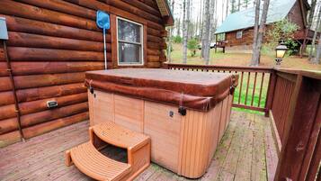 Uma cabana de madeira com banheira de hidromassagem e um banco de madeira no deck.