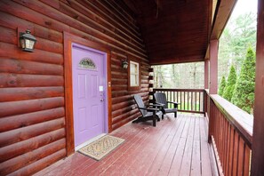 A log cabin with a purple door, two chairs on the porch, and a view of the forest. - 2 Bedroom 2 Bath Cabin with Hot Tub (Beaver, WV) (Beaver)