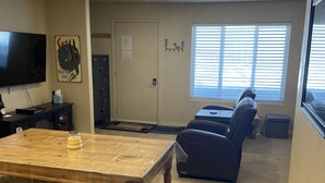 Una sala de estar con una mesa de madera, un televisor y un sofá.