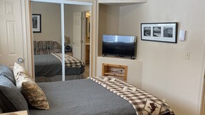 Un dormitorio con cama, televisor, reloj y un cuadro en la pared.