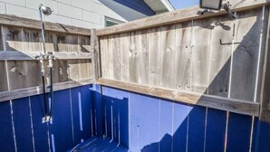 Een houten terras met een blauw geschilderde muur en een klein elektronisch apparaat aan de rechterkant.