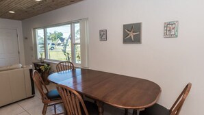 Een eetruimte met een houten tafel en stoelen, een raam met uitzicht en een wand met ingekaderde foto's.