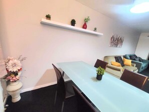 Un salon moderne avec une table à manger, des chaises, un canapé et une petite plante en pot posée sur la table.
