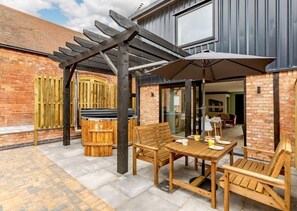 Enjoy al fresco dining and relaxation under a shaded pergola with a wooden table and bench.