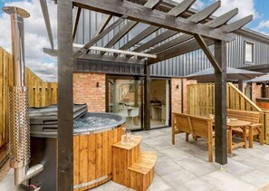Relax in the patio area with a hot tub and comfortable seating under a covered pergola.