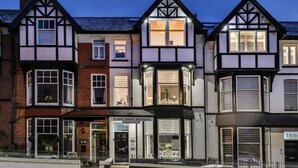 En byggnad i tudorstil med flera fönsterutskott och en butik på bottenvåningen.