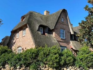 Uma casa com um telhado de palha distinto e paredes de tijolo.