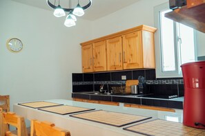Une cuisine avec des meubles de rangement en bois, un plan de travail noir, un évier et une fenêtre.