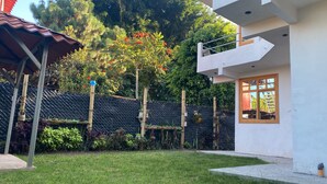 Une maison moderne dotée d’un balcon, d’un jardin clôturé et d’une grande variété de plantes.