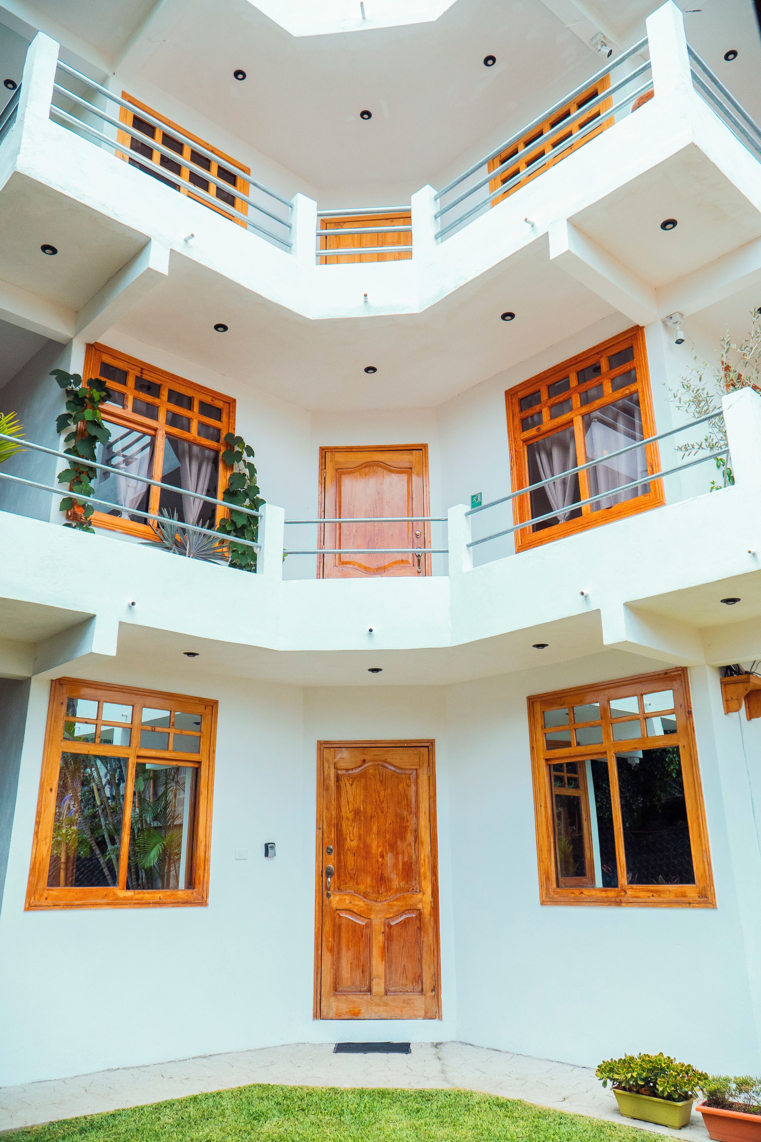 A multi-level building with balconies, a central door, and potted plants.