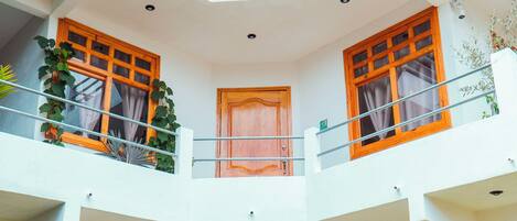 A multi-level building with balconies, a central door, and potted plants.