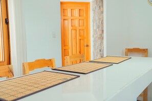Une table à manger recouverte d’une nappe blanche, avec des chaises en bois.