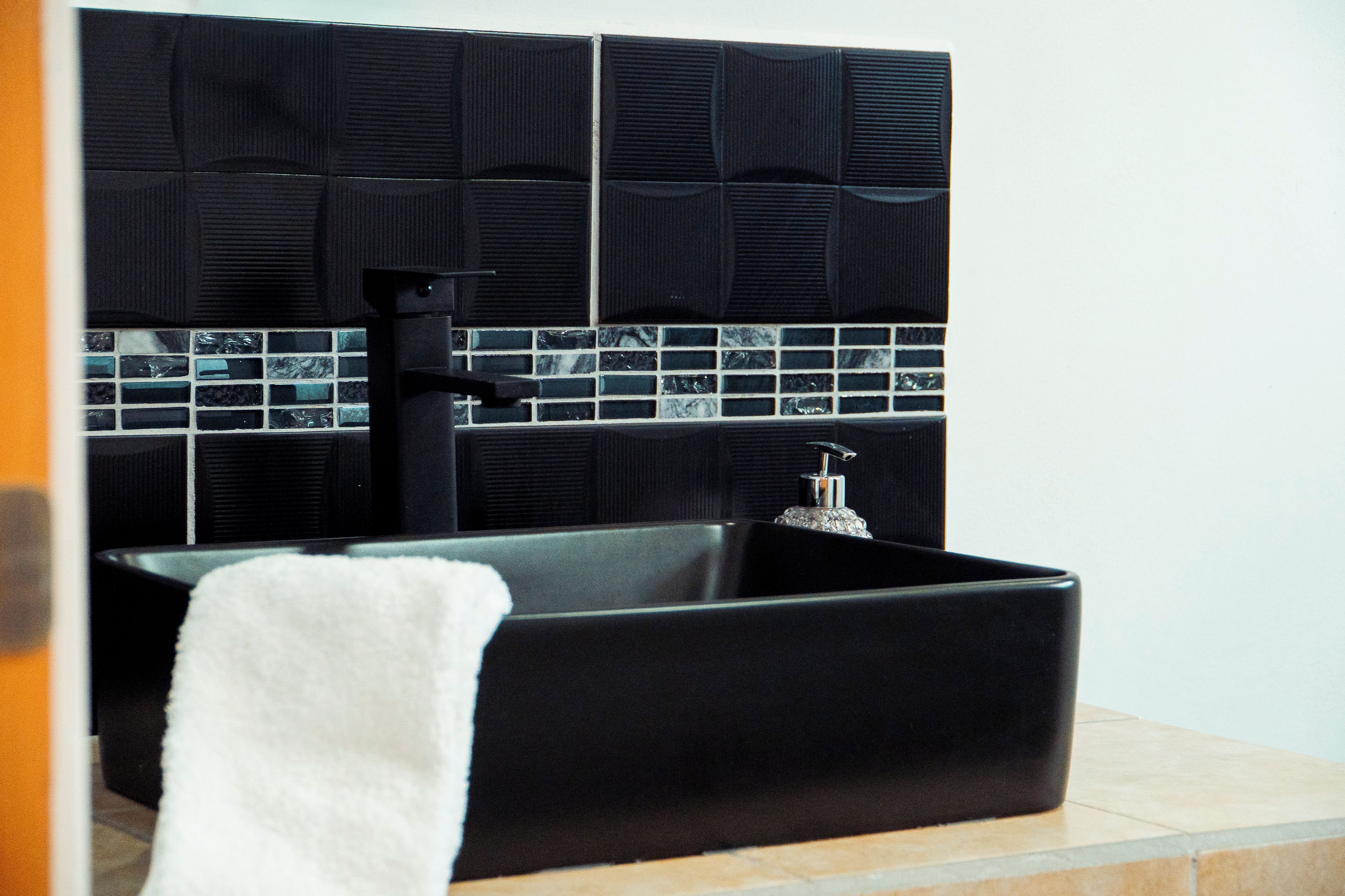 Un lavabo negro rectangular con un grifo y una toalla a la izquierda.