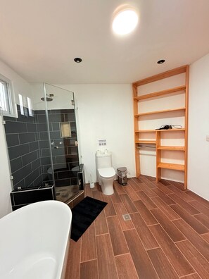 Uma casa de banho moderna com chuveiro, sanita e banheira.