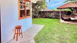 Une maison moderne dotée d’un patio, d’un tabouret en bois et d’une chaise suspendue.