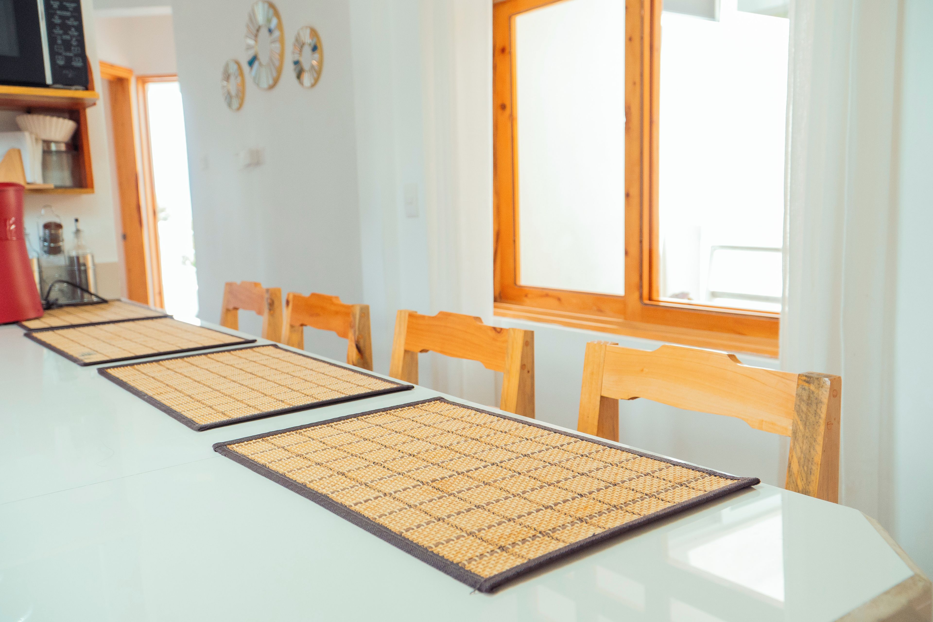 Una mesa de comedor con individuales trenzados, sillas de madera y un ventanal con vistas.