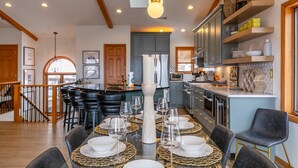 A modern kitchen with grey cabinets, a stainless steel refrigerator, and a built-in oven.