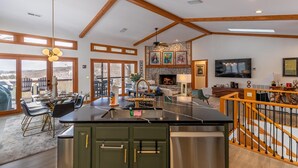 A spacious kitchen with a central island, wooden beams on the ceiling, and a fireplace.