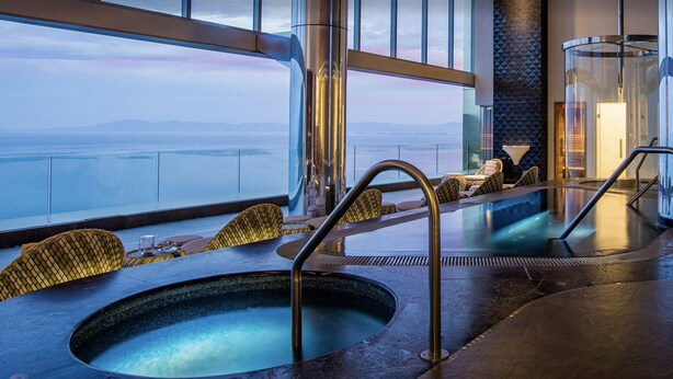 A spa area with two hot tubs, seating, and a view of the ocean. - Junior Panoramic Suite Pureto Vallarta (Puerto Vallarta)