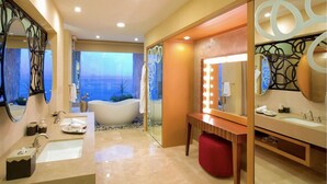 A modern bathroom with a large bathtub, a vanity with a mirror, and a view of the cityscape. - Junior Panoramic Suite Pureto Vallarta (Puerto Vallarta)