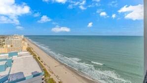 Ein Küstenhotel mit Blick auf den Strand, einen klaren Himmel und eine ruhige See.
