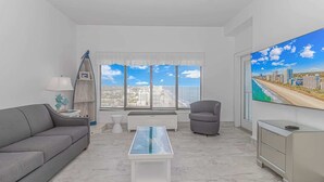 Ein modernes Wohnzimmer mit einer Couch, einem Sessel, einem Couchtisch, einem Fernseher und einem Fenster mit Jalousien.