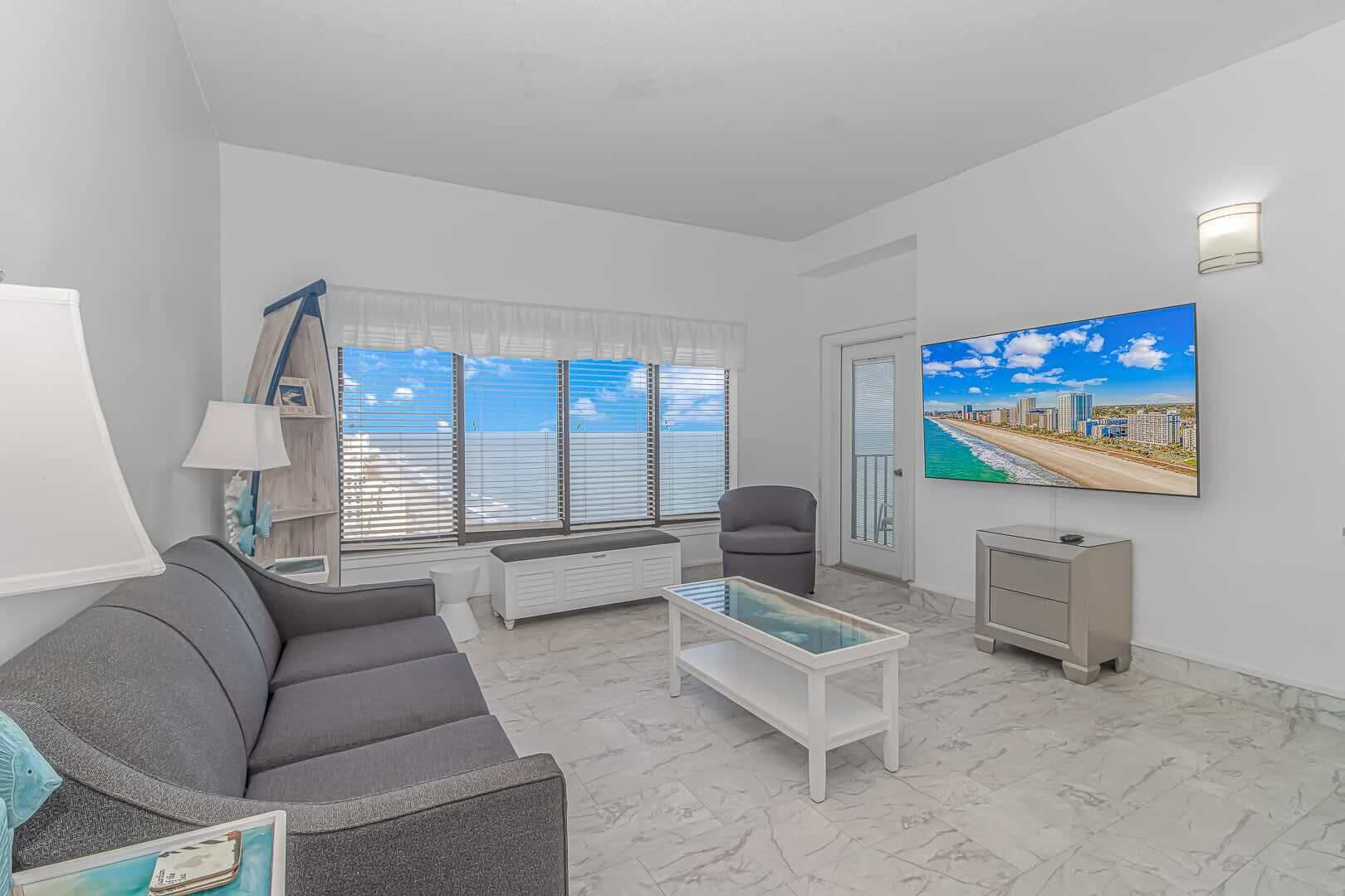 A modern living room with a sofa, coffee table, and a painting of a beach cityscape.