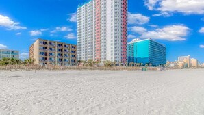 Ein Strandhotel mit mehreren Etagen, Balkonen und freiem Blick auf den Ozean.