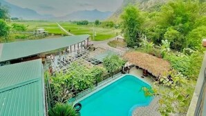 A swimming pool surrounded by lush greenery and a mountain backdrop. - Homestay An Huy Mai Châu (Mai Chau)