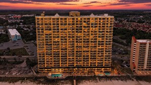 A high-rise hotel with multiple floors, a swimming pool, and a view of the surrounding cityscape. - "Emerald Isle" | Beachfront | Amazing beach views | Heated Community Pool | Fitness center (Panama City Beach)