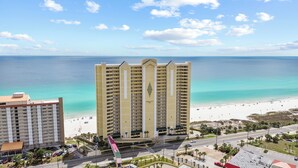 A high-rise hotel with a beach view, multiple balconies, and a parking area. - "Emerald Isle" | Beachfront | Amazing beach views | Heated Community Pool | Fitness center (Panama City Beach)