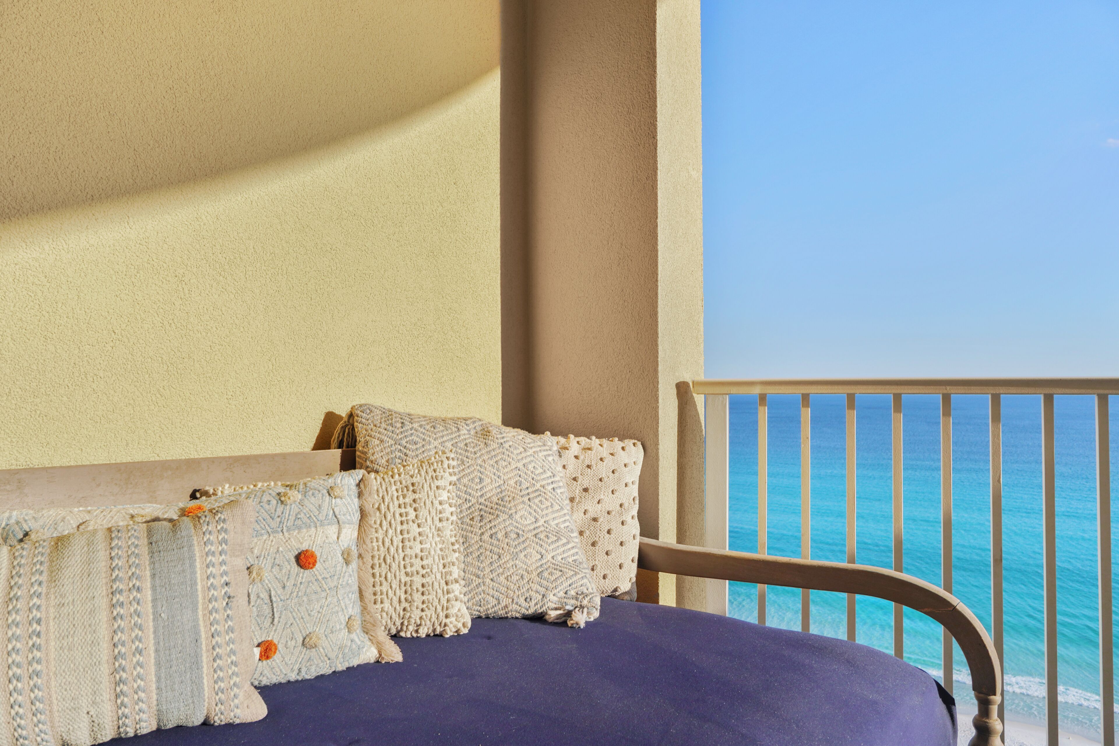 A bed with a blue bedspread, a wooden headboard, and multiple pillows.