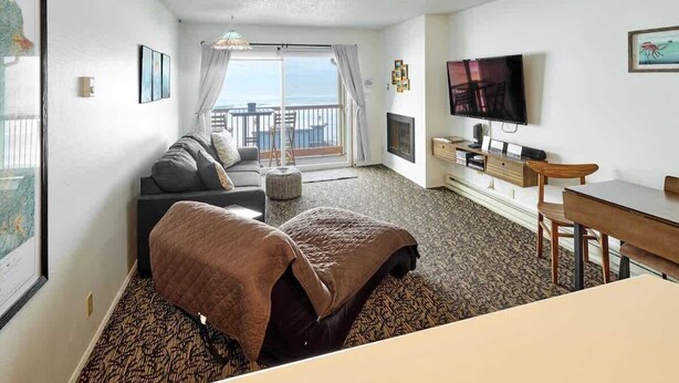Ett hotellrum med en säng, en soffa, en TV, ett skrivbord och en balkong med utsikt.