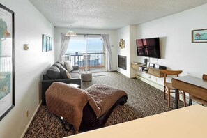 A hotel room with a bed, a sofa, a TV, a desk, and a balcony with a view.