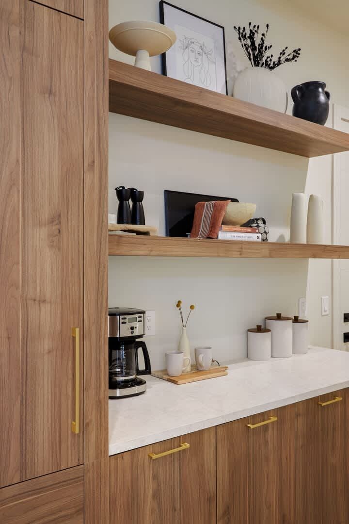 Una cucina con mobili in legno, un piano di lavoro bianco e diversi utensili da cucina.