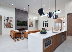 A modern kitchen with a central island, a dining area with a sofa, and a fireplace. - Luna Luxe - Pool Heat Avail- Hot Tub - Fire Pit! (Scottsdale)