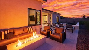 An outdoor living area with a fire feature, a sofa, and lounge chairs. - Luna Luxe - Pool Heat Avail- Hot Tub - Fire Pit! (Scottsdale)