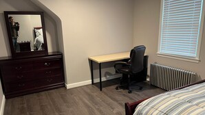 A bedroom with a bed, a dresser, a desk, and a chair. - Cozy 1-bedroom apartment with king size bed. (Towson)