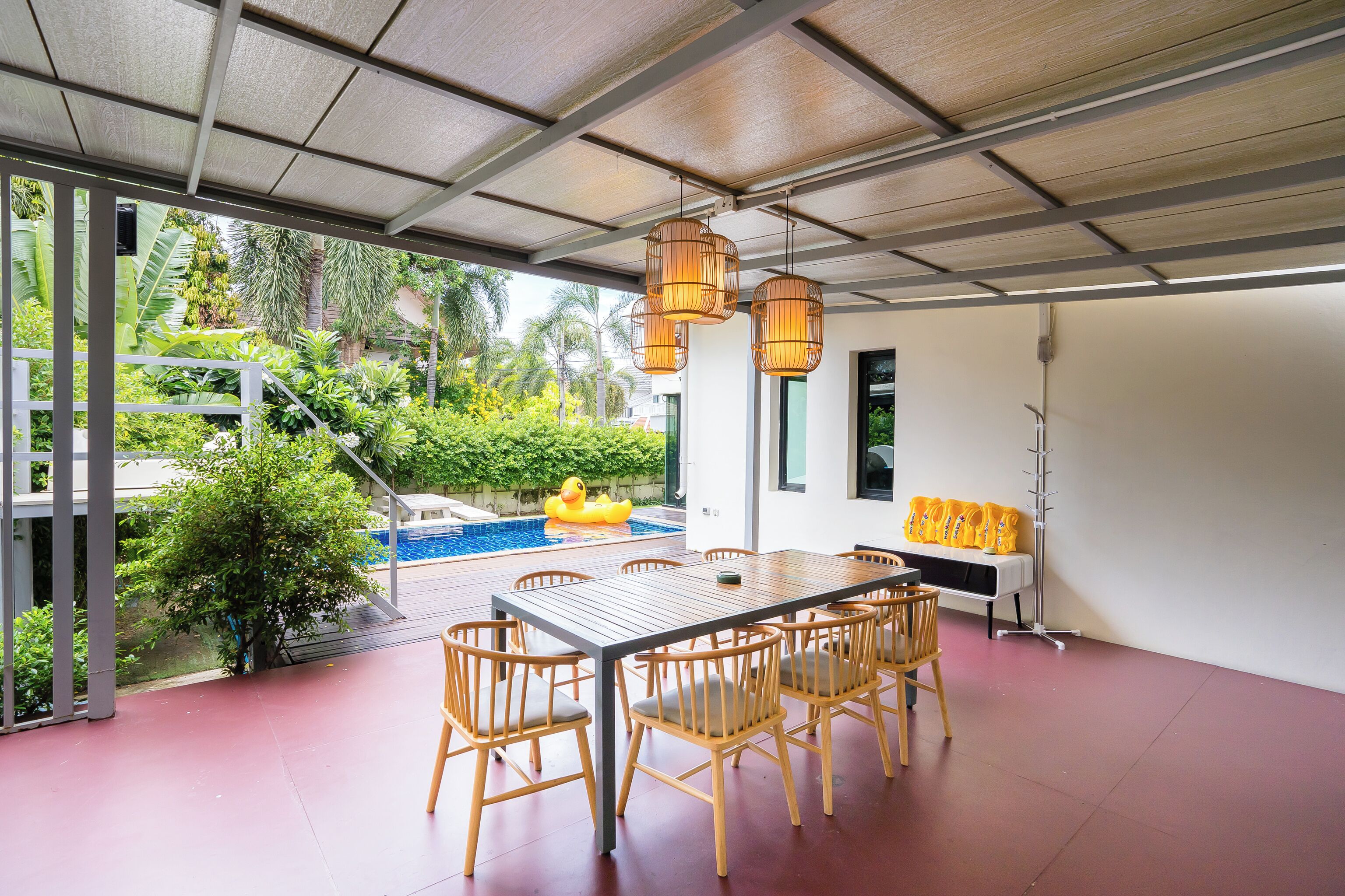 Un espace extérieur abrité, aménagé pour les repas, avec une piscine et de la verdure en arrière-plan.