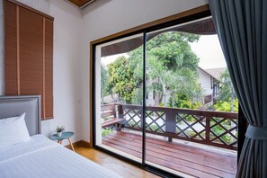 A bedroom with a large sliding glass door leading to an outdoor deck. - Natcha Pool Villa by Warin (Pattaya)