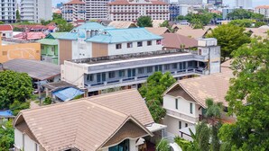 A residential area with houses, a swimming pool, and a large building in the background. - Natcha Pool Villa by Warin (Pattaya)