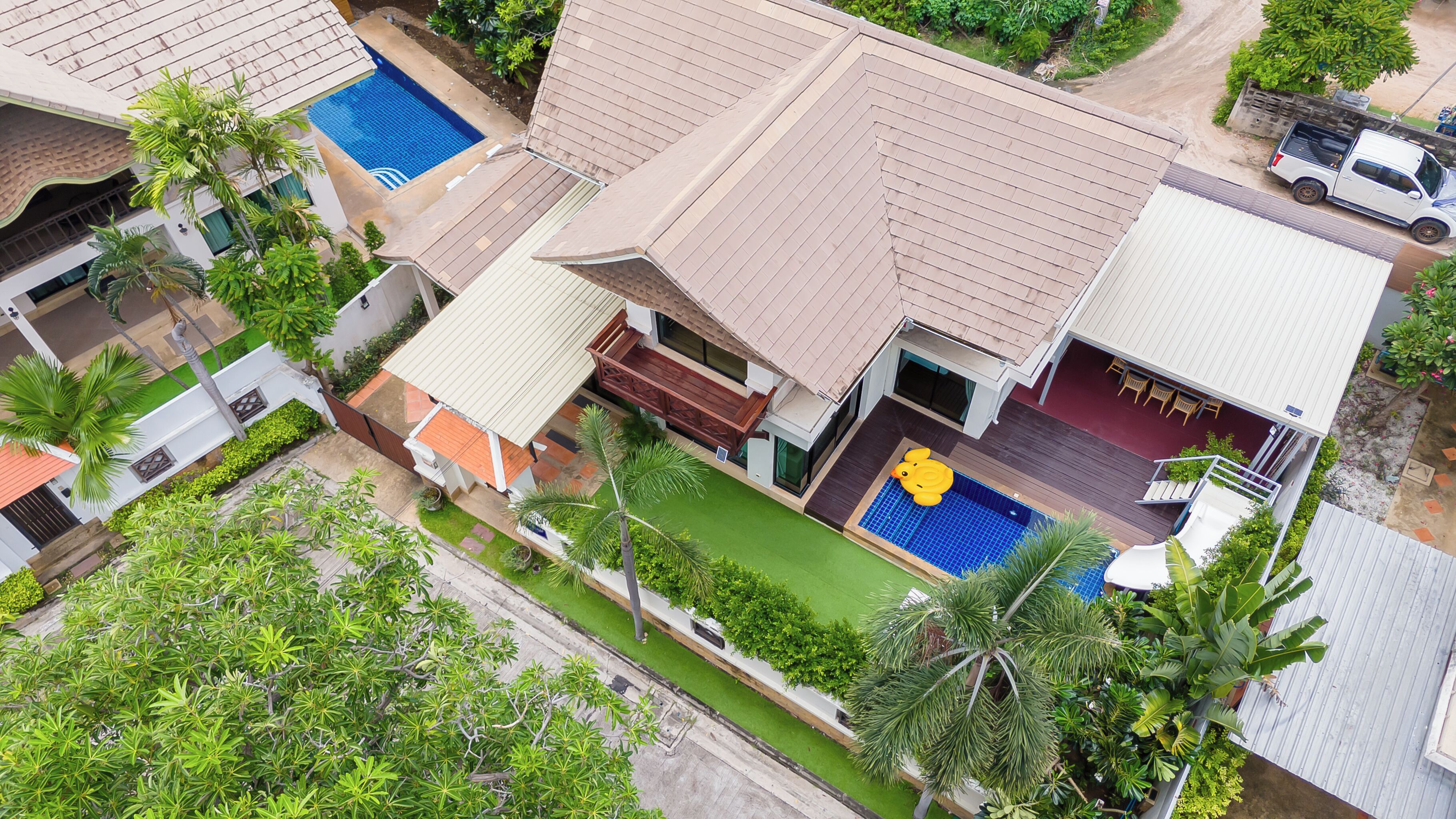 A residential area with multiple houses, each featuring a swimming pool and a well-maintained garden.