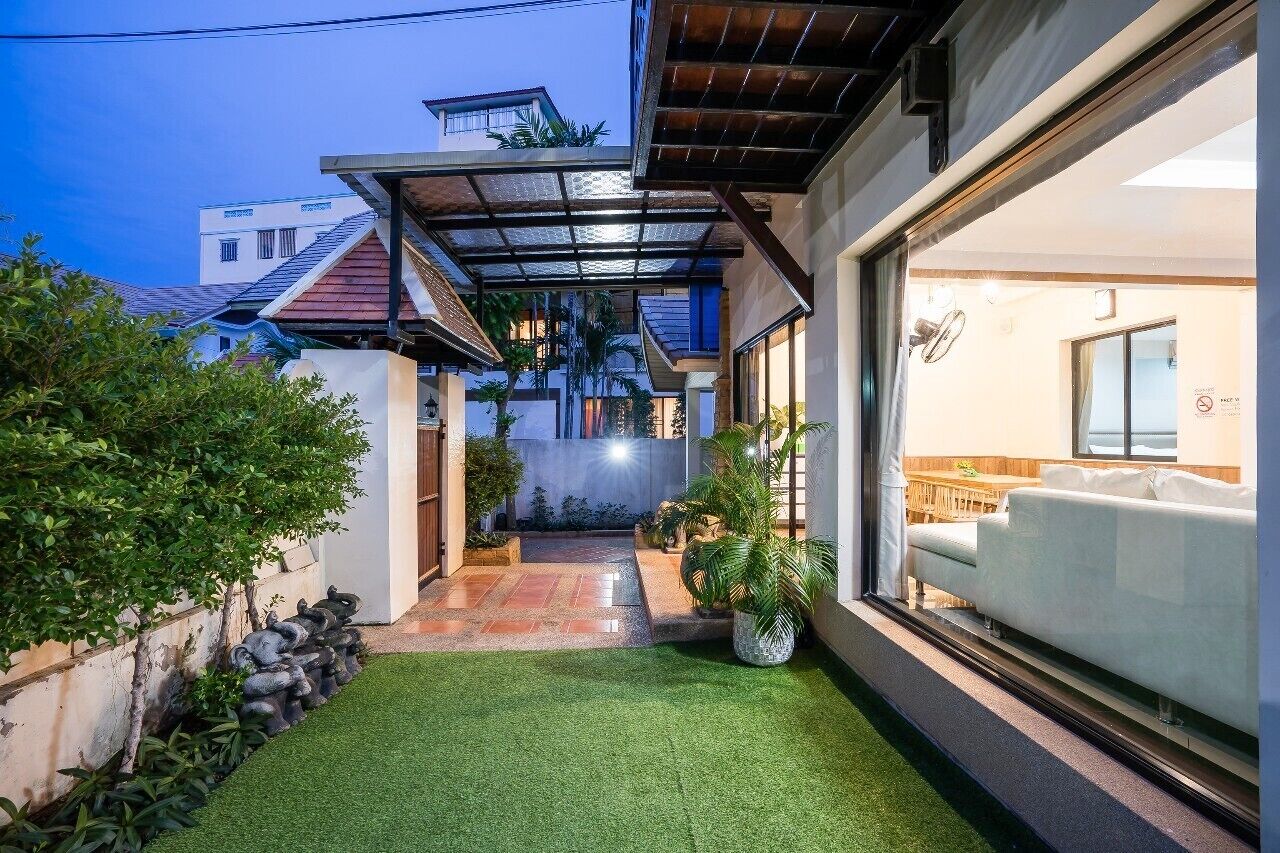 A modern house with a covered patio, artificial grass, and a white sofa.