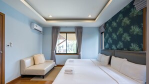 A hotel room with two beds, a sofa, a window with curtains, and a wall with a plant pattern. - Natcha Pool Villa by Warin (Pattaya)