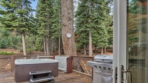 Een terras buiten met een jacuzzi, een barbecue en een houten dek.