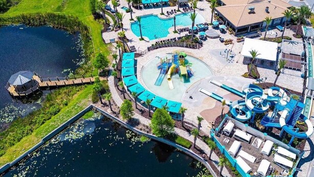 An aerial view of a resort with a central pool, a water slide, and a dock. - Contemporary pool home, gated community, resort facilities! (Haines City)