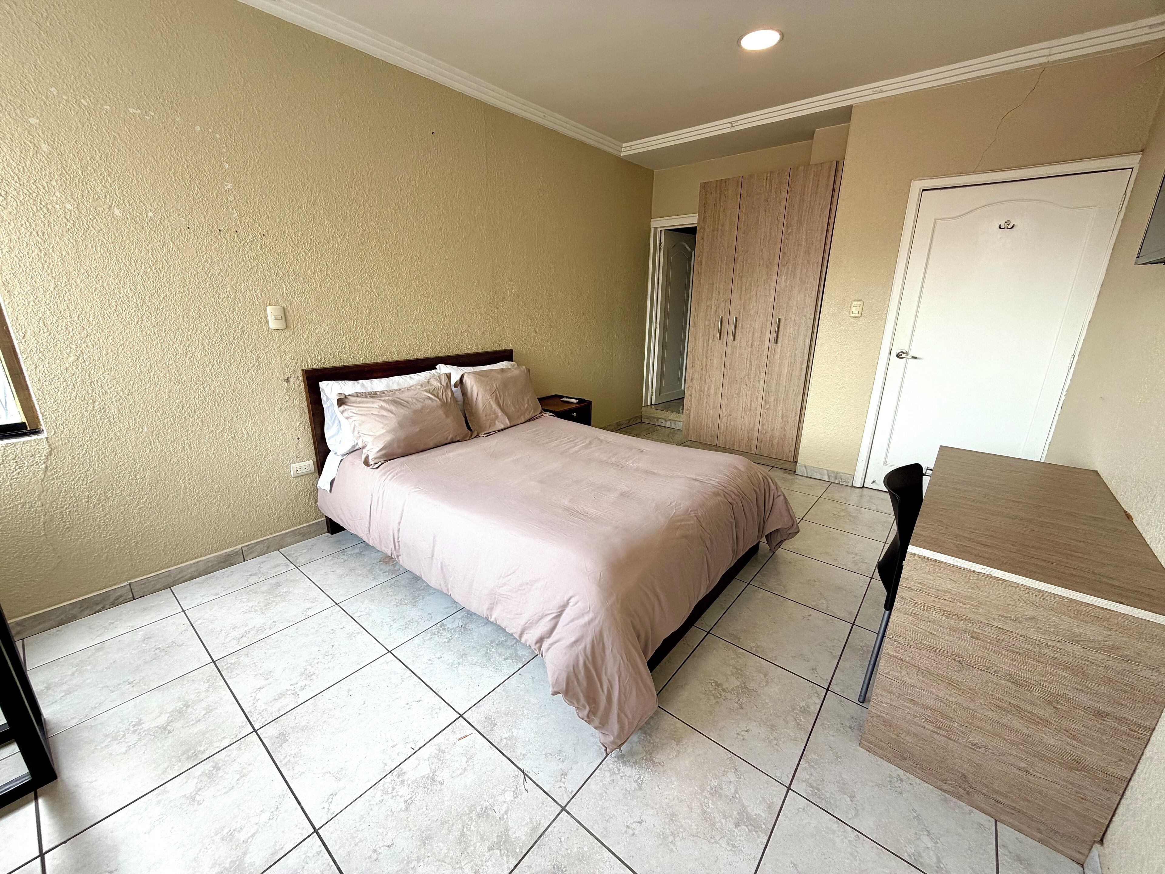 A bedroom with a bed, a wardrobe, and a desk.